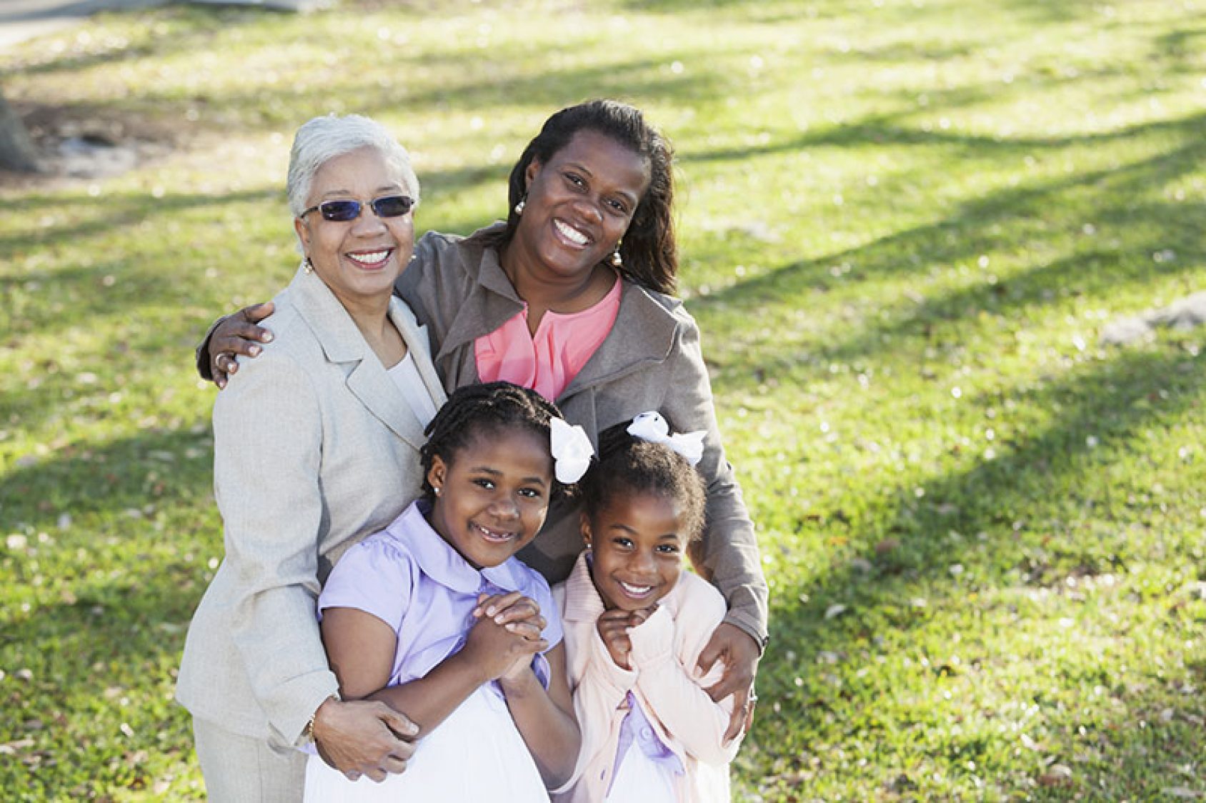 an image of an African-American family embracing each other for a family photo outside at a park