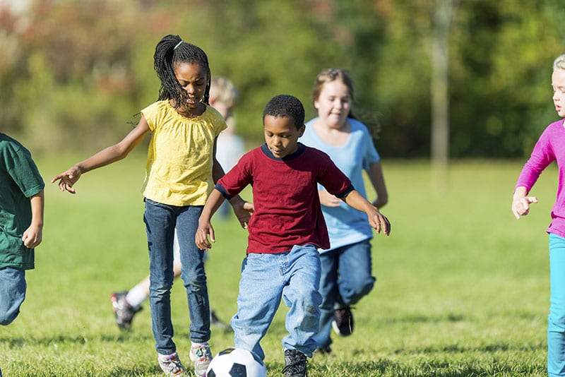 Image of some kids playing soccer in a grassy field